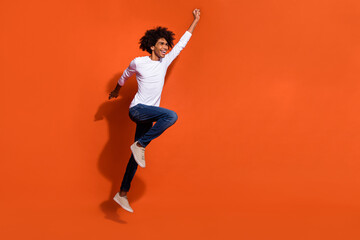 Photo of pretty cool guy dressed white shirt jumping high looking empty space isolated orange color...
