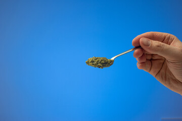 Fresh green Pesto sauce on a metal spoon held by Caucasian male hand. Close up studio shot,...