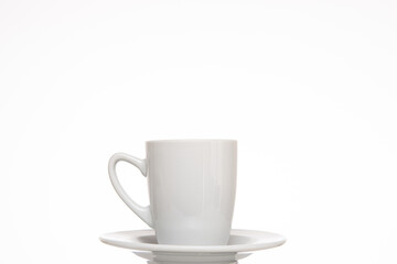 Small white ceramic coffee cup on a plate. Close up studio shot, isolated on white backgrou