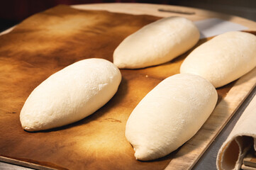 Fototapeta na wymiar several raw loaf of French bread lies on a wooden board. Preparing before baking artisan bread