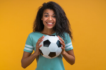 Studio portrait of football fan girl with the ball in hands smiling being happy to support favorite...