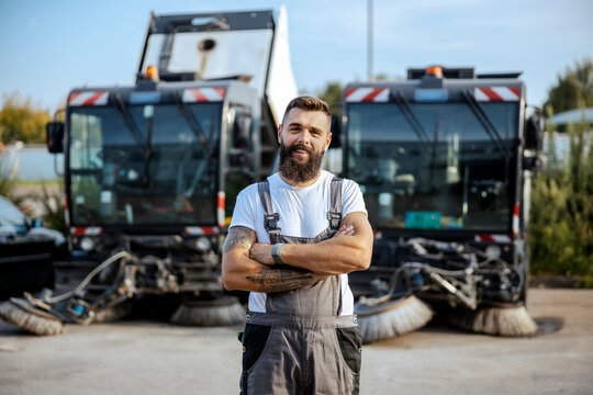 A successful auto-mechanic standing outdoors with arms crossed and smiling at the camera.