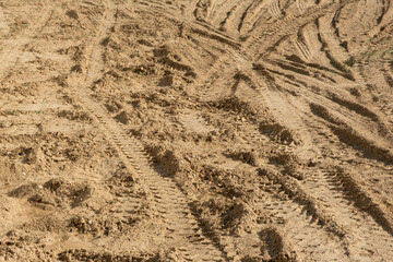 Wet sandy ground covered with car tire tracks. Selective focus.