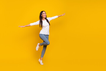 Fototapeta na wymiar Full length photo of young adorable lady have fun hands wings airplane isolated over yellow color background