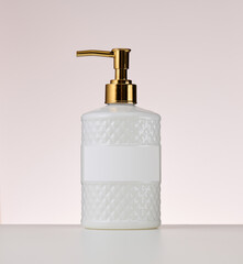 white plastic container with a golden dispenser on a beige background