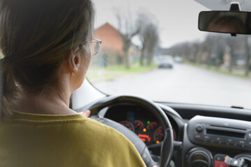 Woman driving. Rear view of a woman driving a car. Glasses. Attention to the perspective of the road. Driving school