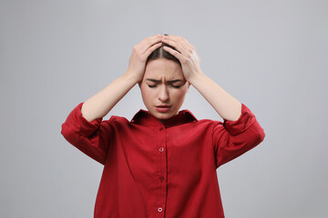 Woman suffering from headache on light grey background. Cold symptoms