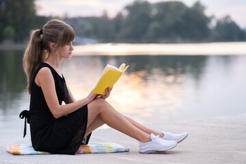 Young woman resting in summer park reading a book. Education and sudy concept