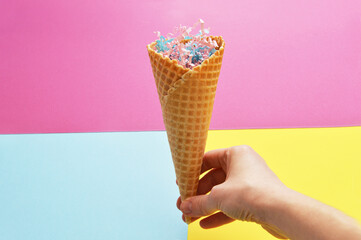 Wafer cup in hand on a bright pink background with paper