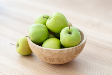 Fresh green apples in a wooden bowl on a wooden table. Healthy eating