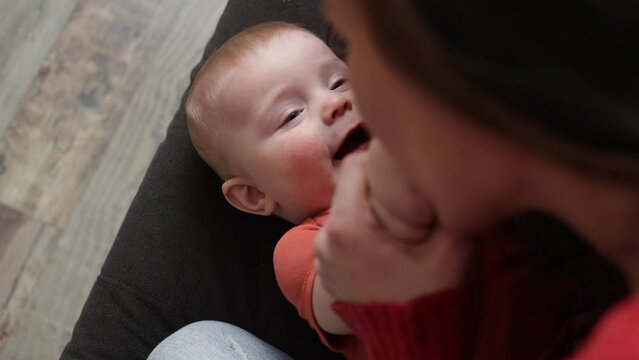 Young cheerful woman playing with her infant bay. Mother spending time with her baby. Motherhood 