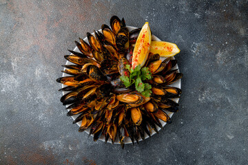 Mussels in tomato sauce with lemon and fried bread on dark stone table top view