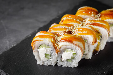 appetizing Philadelphia sushi roll with eel and cucumber on a black stone plate