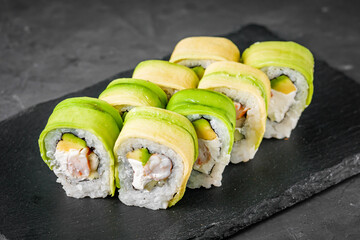 appetizing green dragon sushi roll with philadelphia cucumber shrimp and avocado on a black stone plate