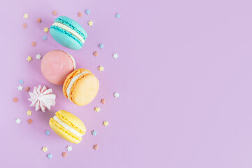 Tasty french macaroons on a violet pastel background.