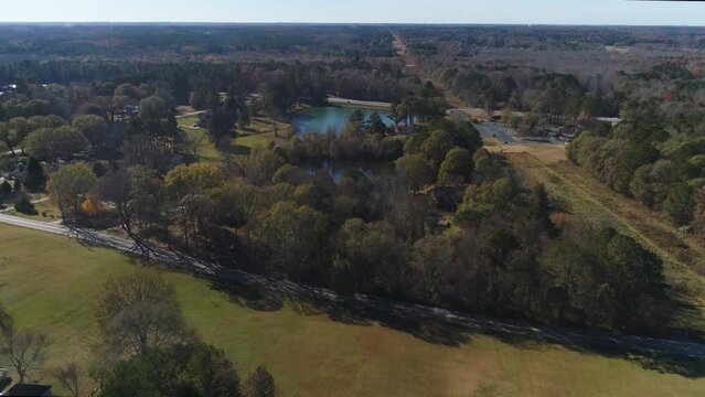 Aerial fly over road to tress and reveal 2 lakes power line paths on the right