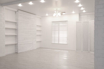 Obraz premium Empty room with textured wall, stylish wooden shelves and large window