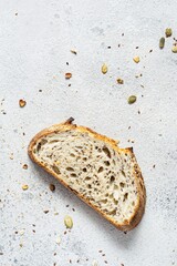 Fresh homemade bread (slice) from whole grain sourdough flour with the addition of bran, seeds (sunflower, pumpkin, flax, sesame) and oatmeal flakes. Healthy food. High quality photo.