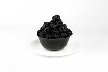 Ripe sweet blackberry in ceramic bowl on white background.