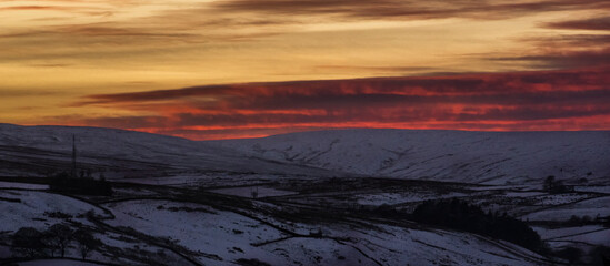 Dramatic, blazing sunset over snow covered hills and mountains  and TV mast (Weardale, the North Pennines, County Durham, UK) - obrazy, fototapety, plakaty