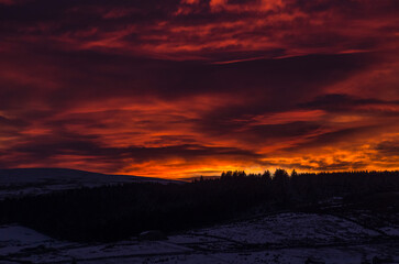 Dramatic, blazing sunset over snow covered hills and mountains (Weardale, the North Pennines, County Durham, UK)