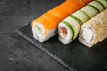 appetizing set of sushi roll on a black stone plate