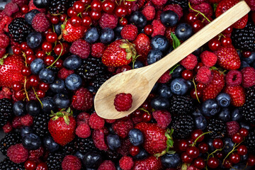 Fresh different berries backgrounds and wooden spoon. Strawberry, blueberry, raspberry red currant and blackberry mix. Top view, flat lay.