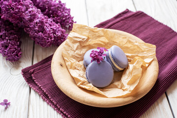 purple macaroons and lilacs on a white wooden background. place for text