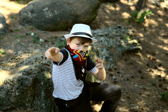 a boy in a cowboy bandanna against the background of huge stones