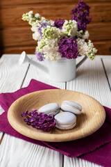 Fototapeta na wymiar purple macaroons and lilacs on a white wooden background. place for text