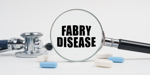 On a white surface lie pills, a stethoscope and a magnifying glass with the inscription - FABRY DISEASE
