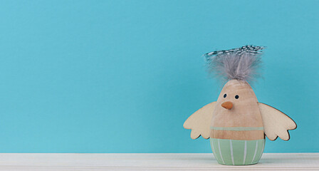One Easter decorative wooden chicken figurine on blue background with copy space. Minimal concept for Easter.