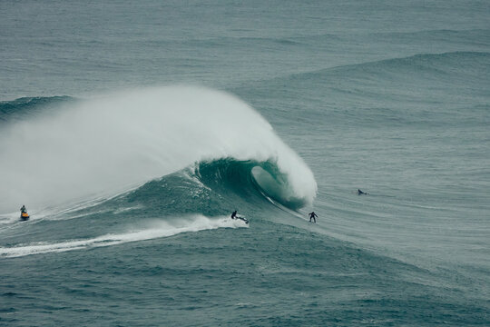 Surfers and jetski on big waves in Nazare