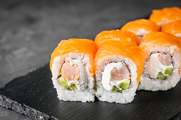 appetizing sushi roll philadelphia with shrimp cheese cucumber and salmon on a black stone plate