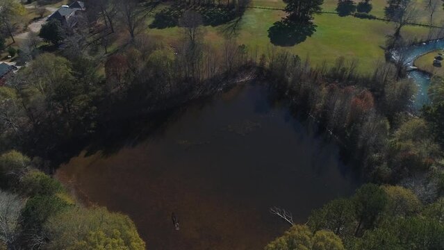 Aerial circle of brown lake with sun shadow glimpse across the lake countryside