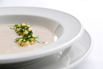 corn soup or cream with cilantro and corn kernels served in white plate on white background