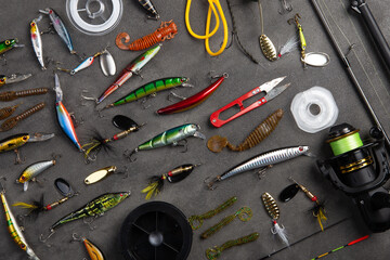 Fishing tackle - fishing spinning rod, hooks and lures on gray background. Active hobby recreation...