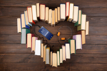 Listening Audio book concept - heart shape of book, headphones and smartphone with audiobook...