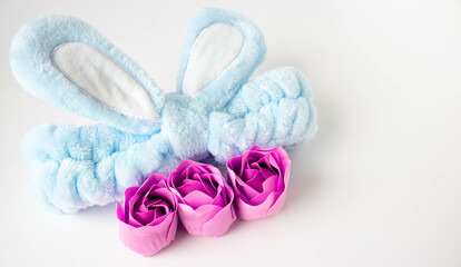 A blue headband with rabbit ears and pink soap roses. Body care. Easter Concept