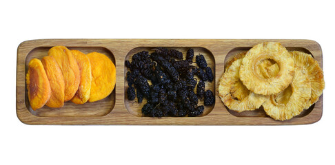 Dried fruits on a wooden platter divided into sections. Dried peach, mulberry and pineapple. Isolated on white background.