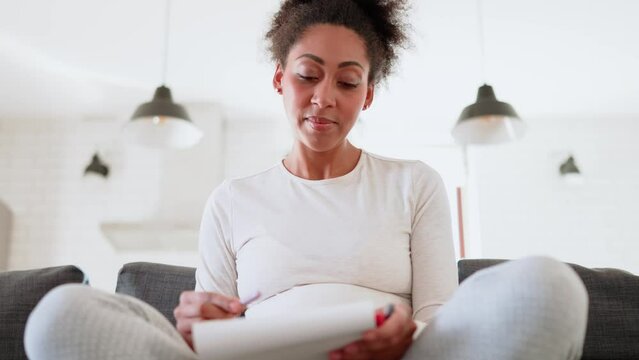 Young African pregnant woman drawing at home