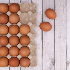 Cardboard box with fresh natural eggs on bright wooden background. Realistic aesthetic concept. Easter holidays arrangement