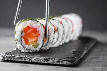 appetizing sushi roll maki with salmon on a black stone plate © Narsil