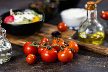 Composition of cherry tomatoes, bowl of salad, jug with oil