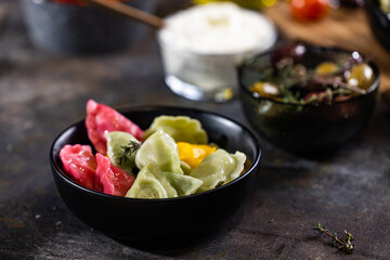 Flat lay composition of bowl of dumplings, jar of sour cream on wooden board
