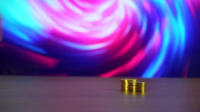 Stacking golden Bitcoins on a table with a psychedelic hypnotic abstract background behind.  	