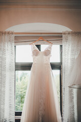 Wedding dress hanging on a cornice in a hotel room during the brides preparations on the day of the wedding © Wolfdography studio