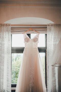 Wedding dress hanging on a cornice in a hotel room during the brides preparations on the day of the wedding