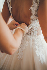 Fastening bride's dress during her preparations on the wedding day