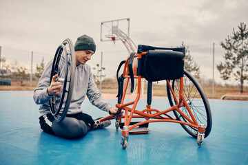 Young basketball player adjusting his sports wheelchair on basketball court.